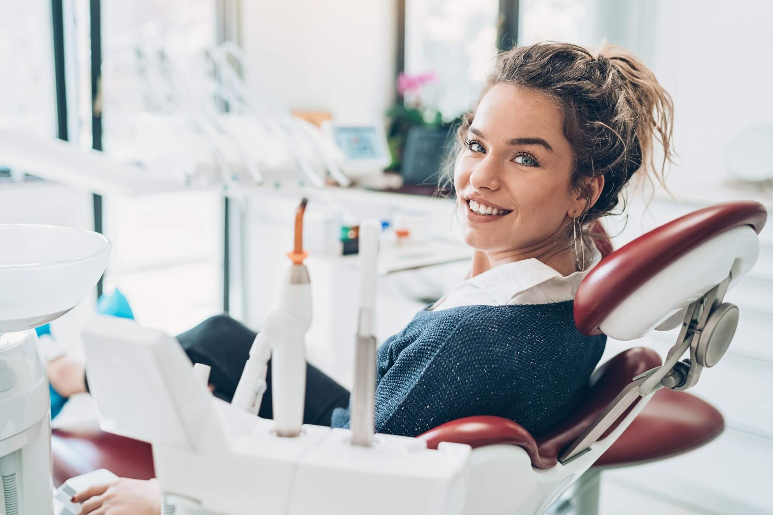 A woman in a dentist chair smiling
