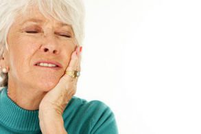 Woman with sensitive teeth holding her jaw at Harwood Dental Care in Bolton