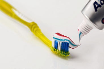 Yellow toothbrush with toothpaste on white background