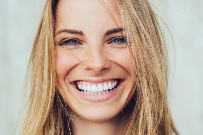 woman smiling with strengthened sensitive teeth after advice by harwood dental care