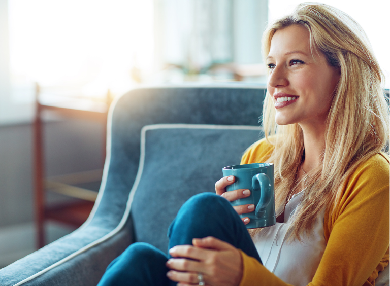woman sat with hot drink after dental implant treatment